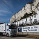 A truck passes a cliff and a sign that says "Welcome to the Ferry Terminal."
