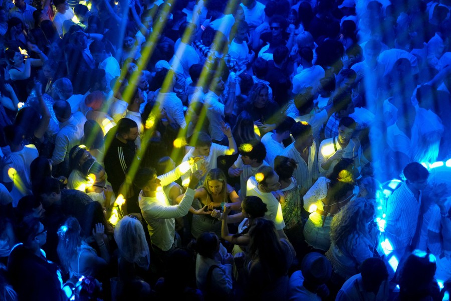 A large crowd of people on a dance floor under blue and yellow lights