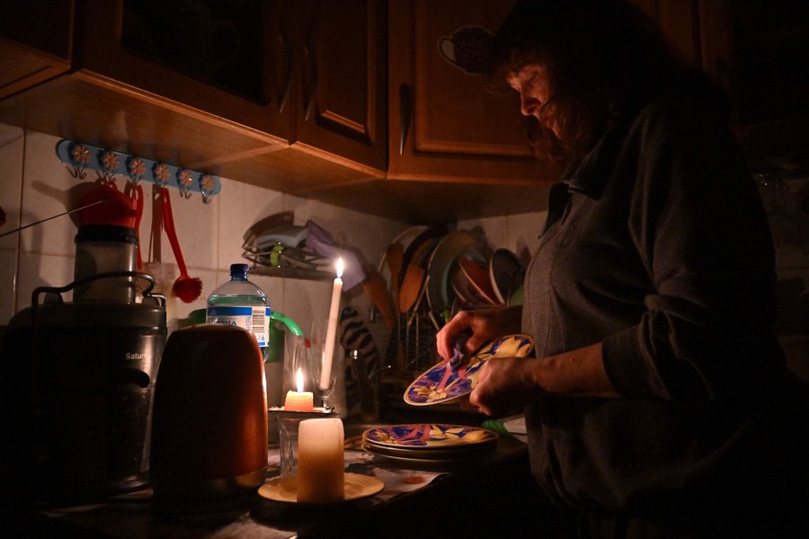 A person washes dishes by candlelight.