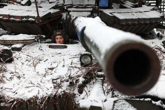 A Ukrainian soldier looks out from a tank and its barrel points at the viewer