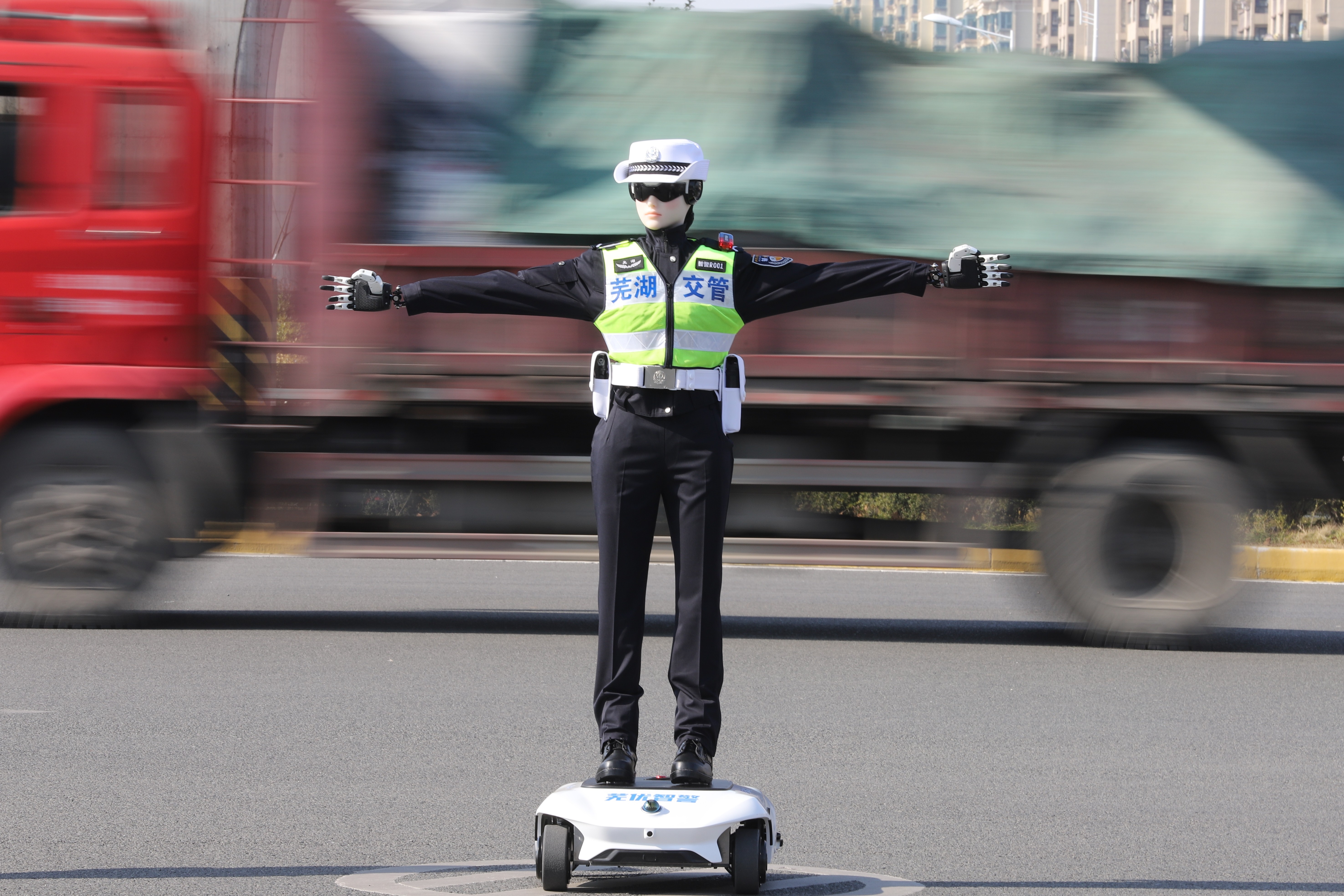 A humanoid robot dressed in a traffic police uniform stands with arms outstretched in a road.
