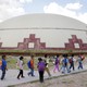 A group of children wearing backpacks walk past a building.