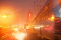 A bus in nighttime streets lit by the glare of streetlights