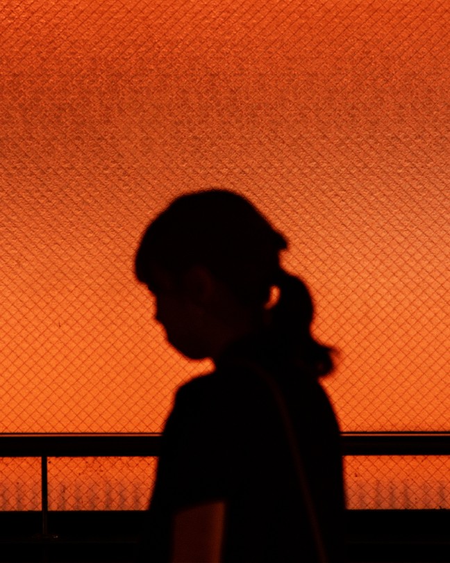 A silhouette of a woman against an orange textured background
