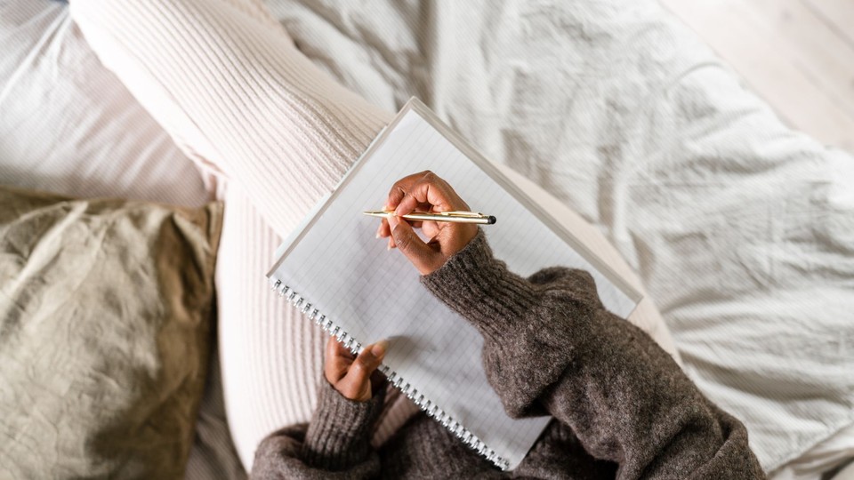 overhead view of person writing in a notebook in bed