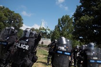 Riot police stand in formation in Charlottesville with a statue of Robert E. Lee behind them.