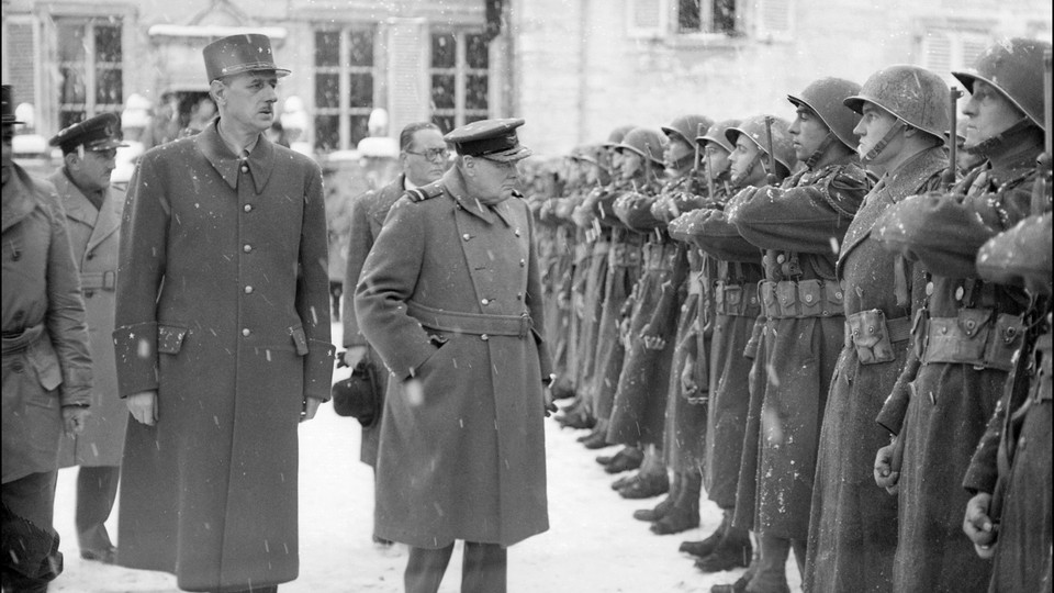 Winston Churchill and General De Gaulle walk past assembled French soldiers under a snowstorm.