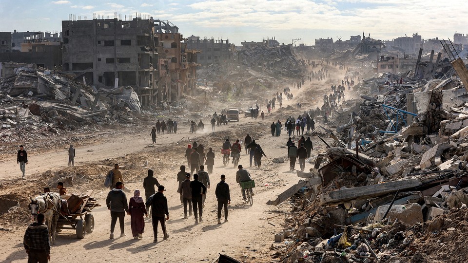 Photo of people walking past rubble in the Gaza Strip