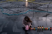 A woman leans over at a candlelight vigil for Ukrainians killed in the towns of Bucha and Irpin.