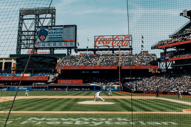 A photograph of a live baseball game from behind a net.