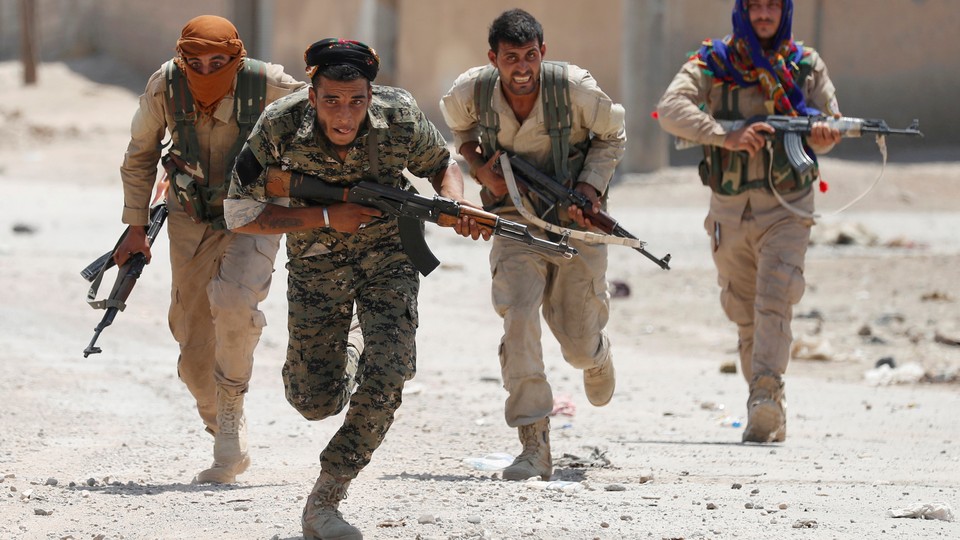 YPG fighters run through the streets of Raqqa, in Syria.