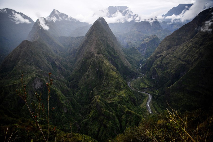 A view from a mountaintop of other nearby mountains covered in lush greenery and clouds