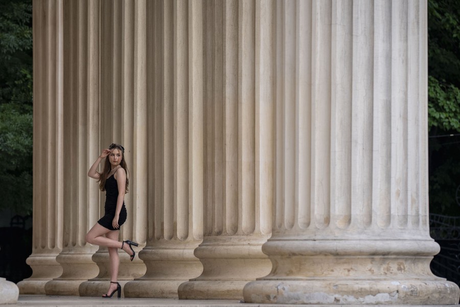 A person poses beside several large columns.