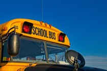 The top of a yellow school bus in front of a blue sky