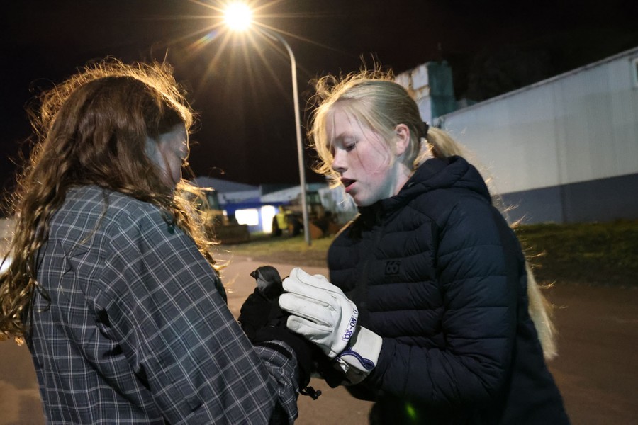 Two people gently hold a small bird.