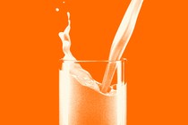 An orange-tinted photo-illustration of milk being poured into a glass