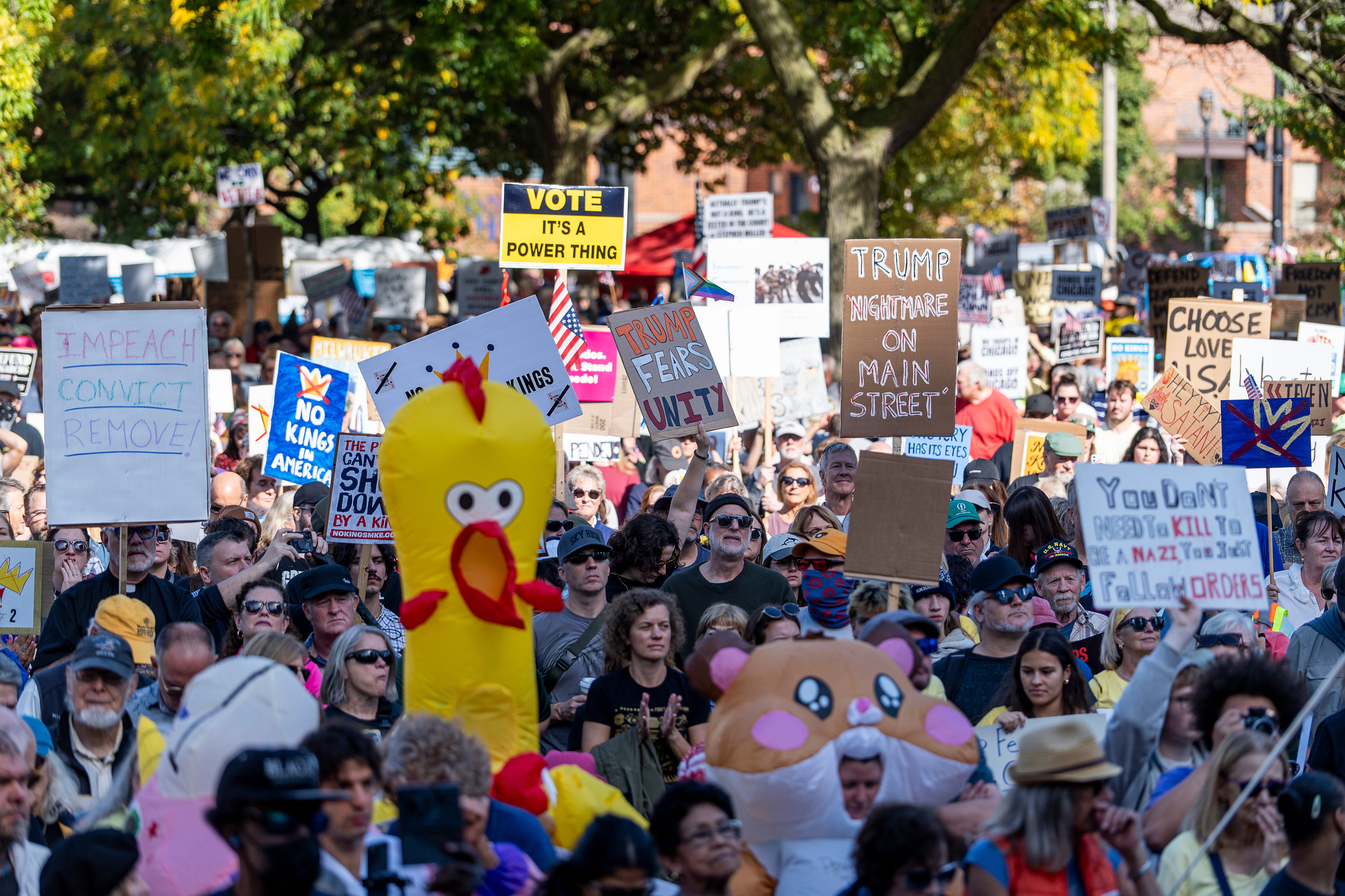 Protesters march and carry signs, including several wearing inflatable animal costumes.