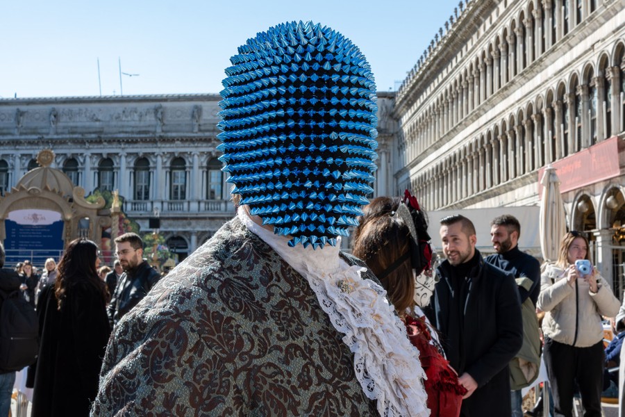 A person wearing a costume and full-head mask covered in short spikes