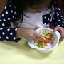 A child eats a bowl of salad.