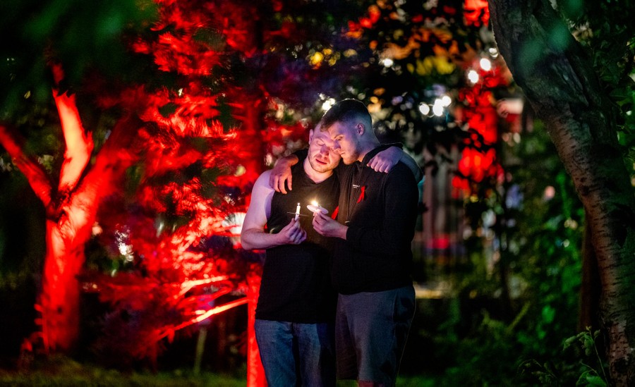 People embrace while attending a candlelight vigil.