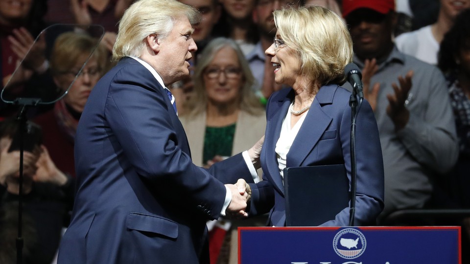 Betsy DeVos and Donald Trump shake hands