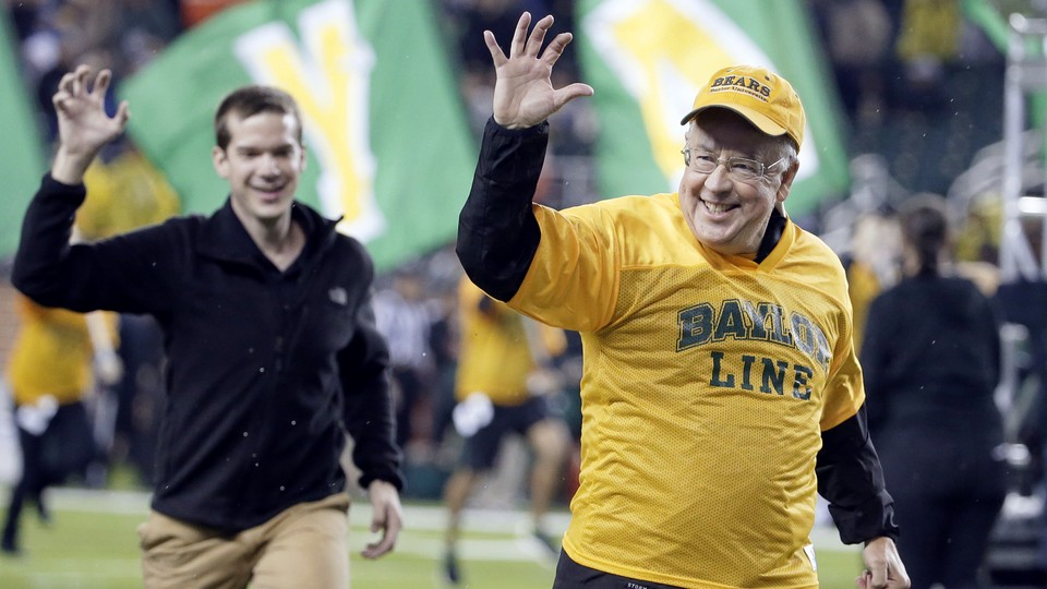 Baylor University President Ken Starr gestures the Sic'em as he leads the freshman class on a run across the field before the start of an NCAA college football game.