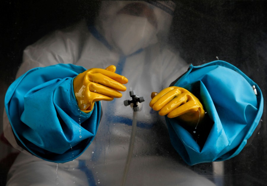 A worker sanitizes large gloves and sleeves.