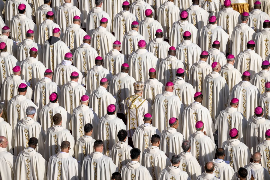 Dozens of priests, bishops, and cardinals, wearing white vestments, stand together in even rows.