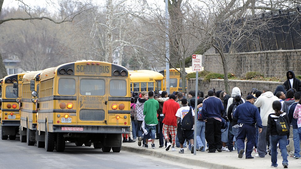 Students walk alongside school buses.