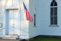 Photograph of a church entrance with an American flag hanging on it