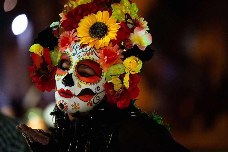 A person in a Catrina mask performs during a parade.