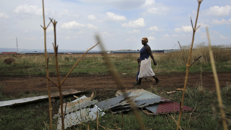 A mother and child walk past corrugated iron left by residents who intended to build an informal settlement.