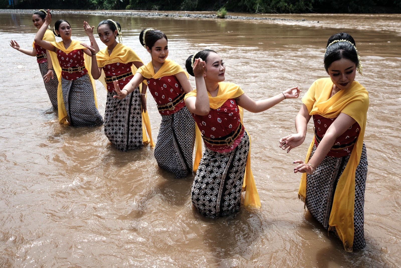 Six dancers perform in a shallow river.
