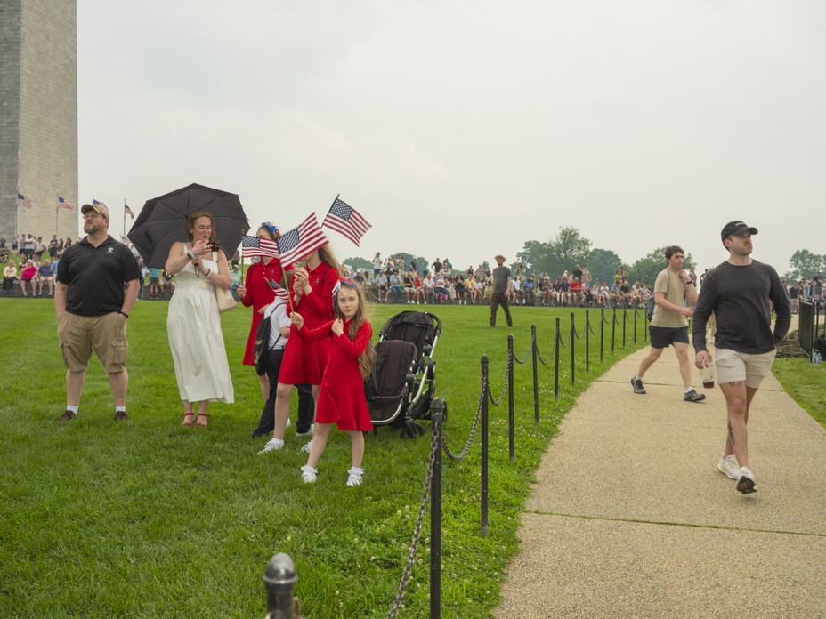 Picture of parade-goers waving flags beneath the Washington Monument.