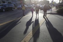 Parents cross the street with their children. 