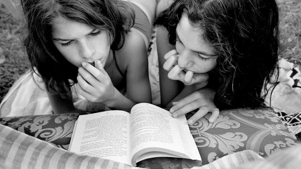 black and white photo of two girls reading a book