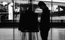 A photo of a voter in silhouette using a voting booth at a polling station