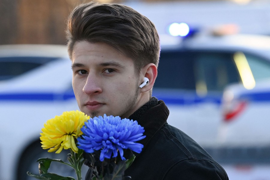 A young man carries blue and yellow flowers.
