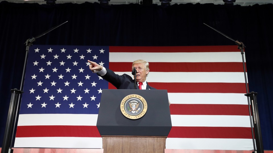 Donald Trump stands in front of an American flag.