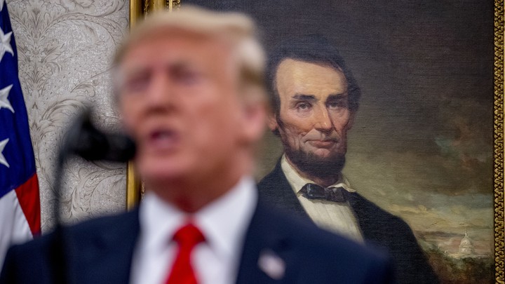 Donald Trump standing in front of a painting of Abraham Lincoln