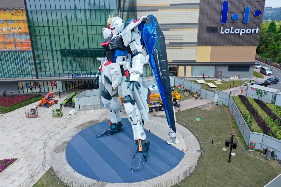 The statue of a gigantic robot stands in front of a shopping mall.