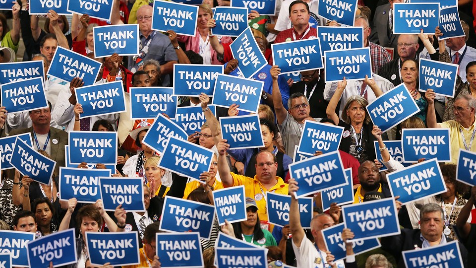 A crowd of people holding blue signs that say THANK YOU