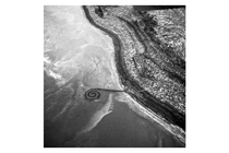 aerial black-and-white photo of spiral earthwork sticking out from shore into lake