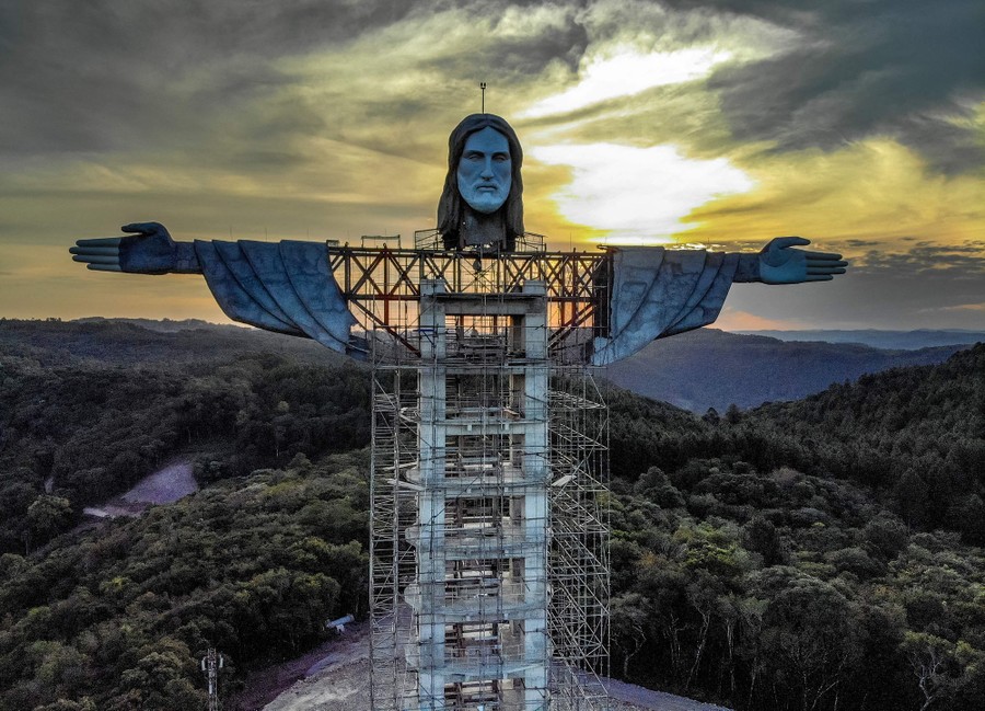 A large statue of Christ is seen under construction.