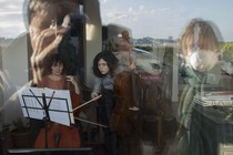 Women playing instruments in a field with masked people, all wobbly