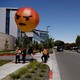 People hold a balloon version of the "angry" emoji.