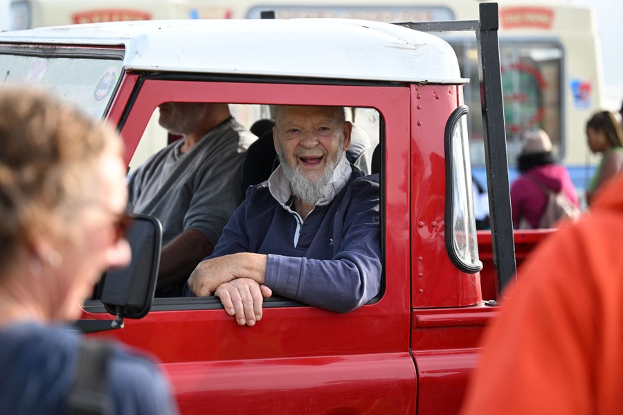 A person smiles while looking out the window of a pickup truck.