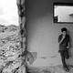A Palestinian youth smokes, leaning against the wall of a ruined house amid rubble in Khan Younis, Gaza, October 2003.