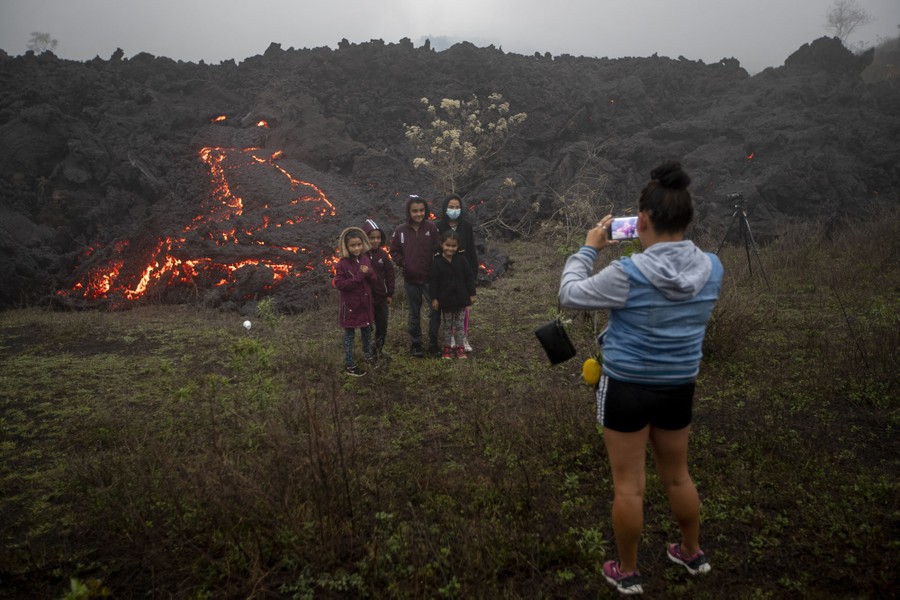 Family members pose for photos near lava.