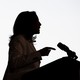Kamala Harris in shadowy profile standing at a microphone-topped lectern